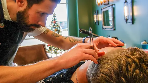 A skilled barber performing an excellent straight razor shave on a client.